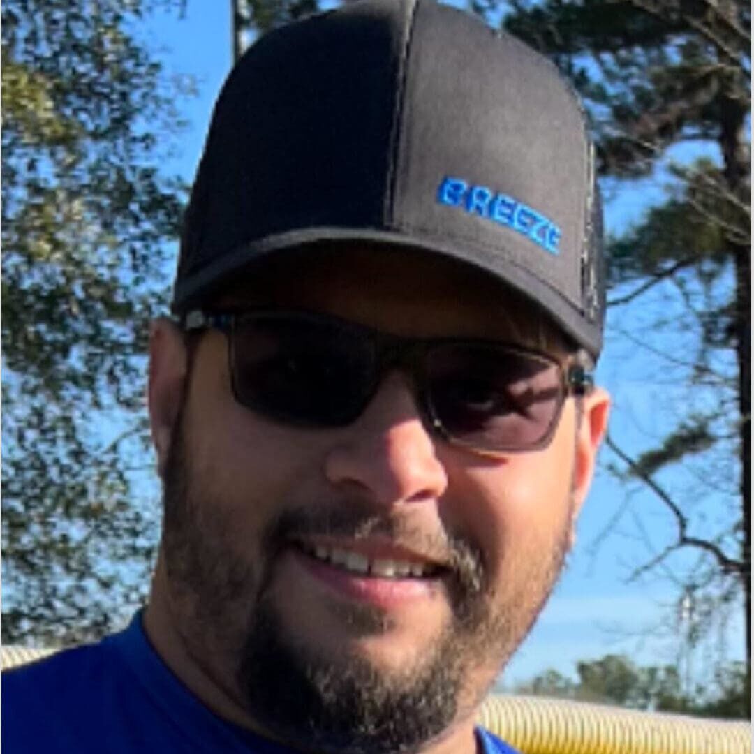 A cropped image of Coach Ramos's face. He is smiling with a cap and sunglasses on