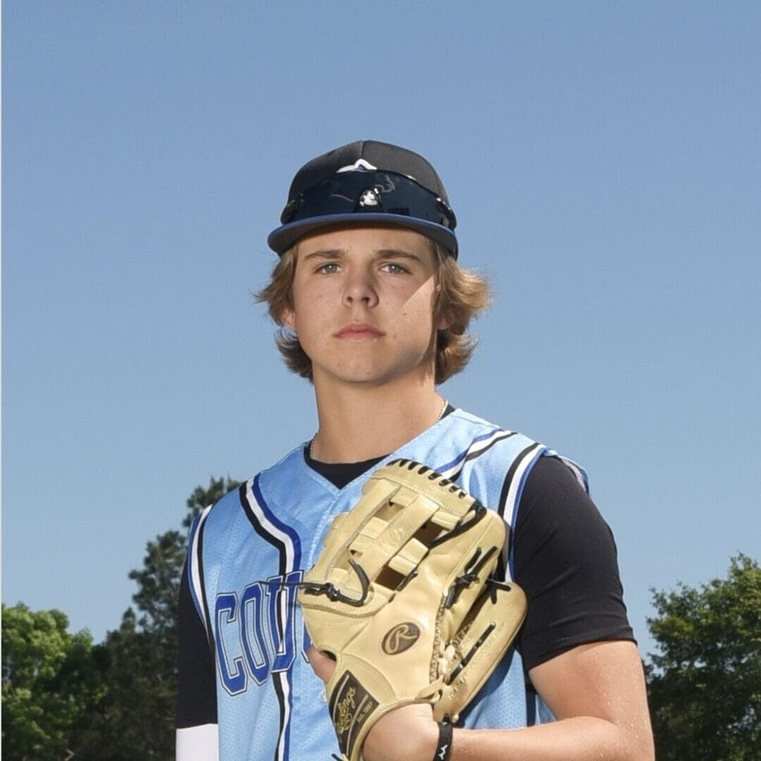 Coach Van House is posing for a professional photo, dressed in his baseball team uniform, with his baseball glove on his hand